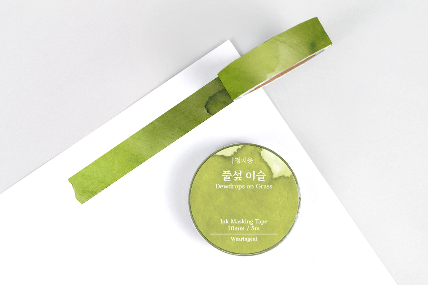 Green masking tape roll and strip on a white background