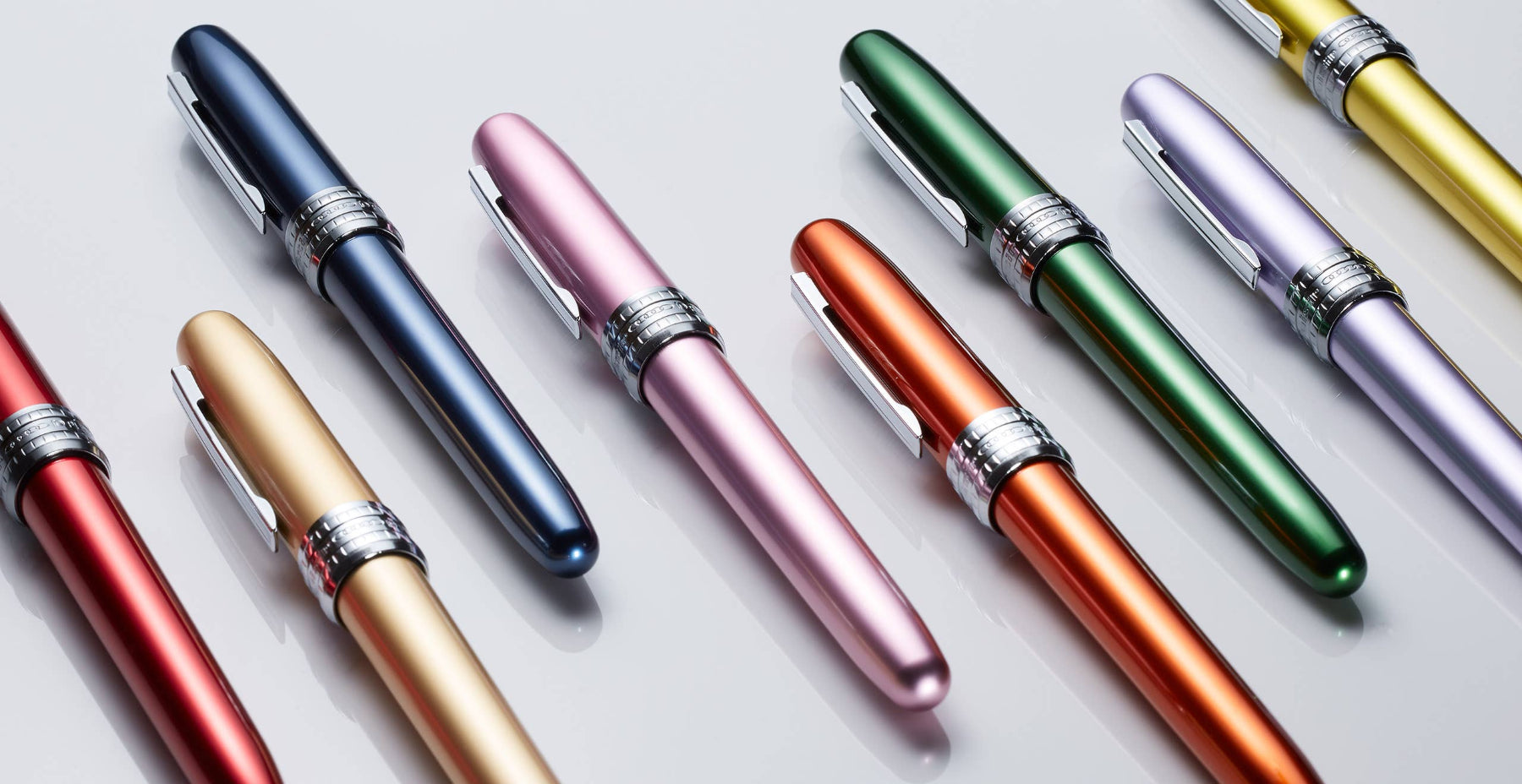 Colorful fountain pens arranged on a light gray background