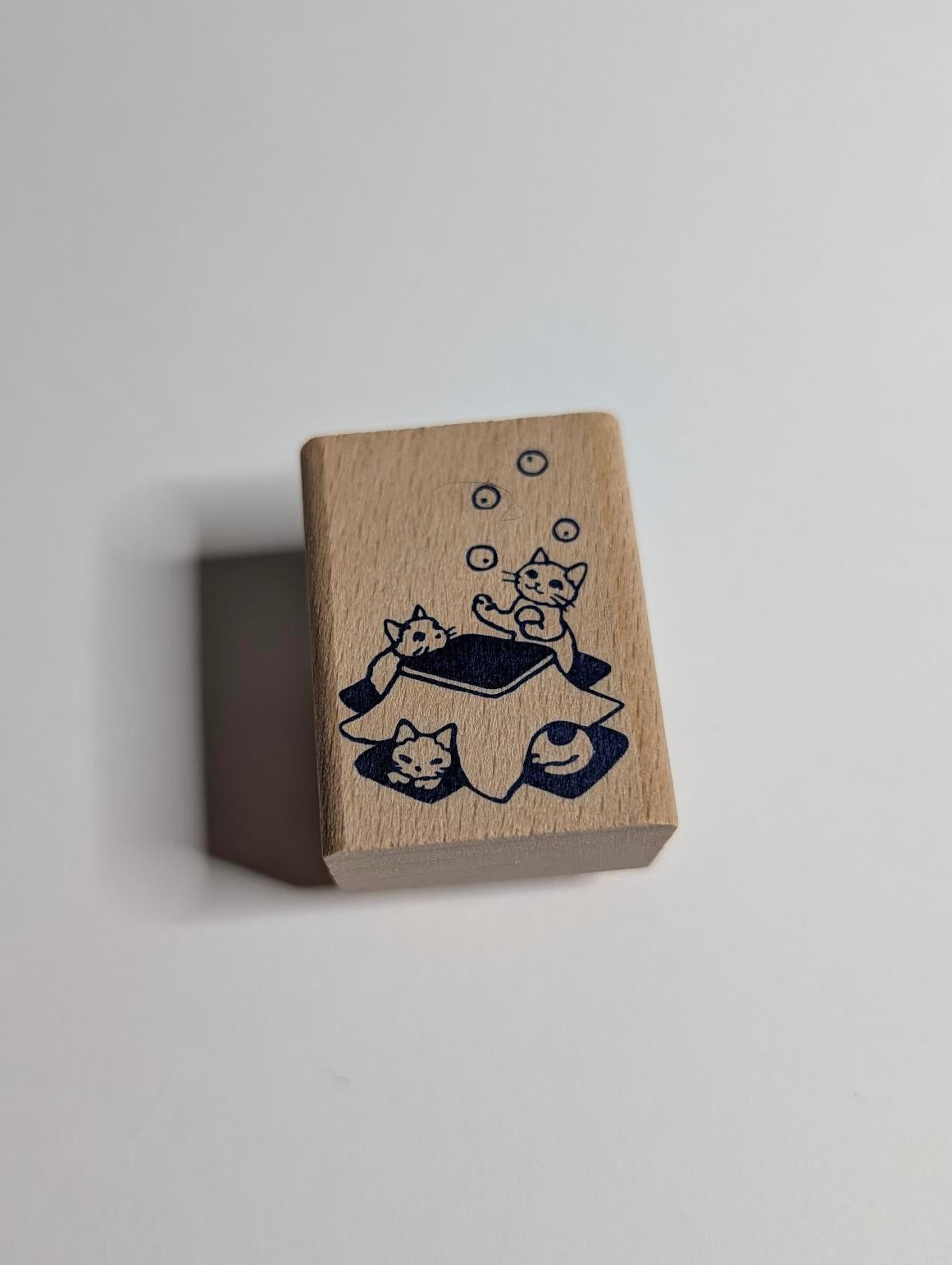 Small wooden block with cat illustrations on a light gray background