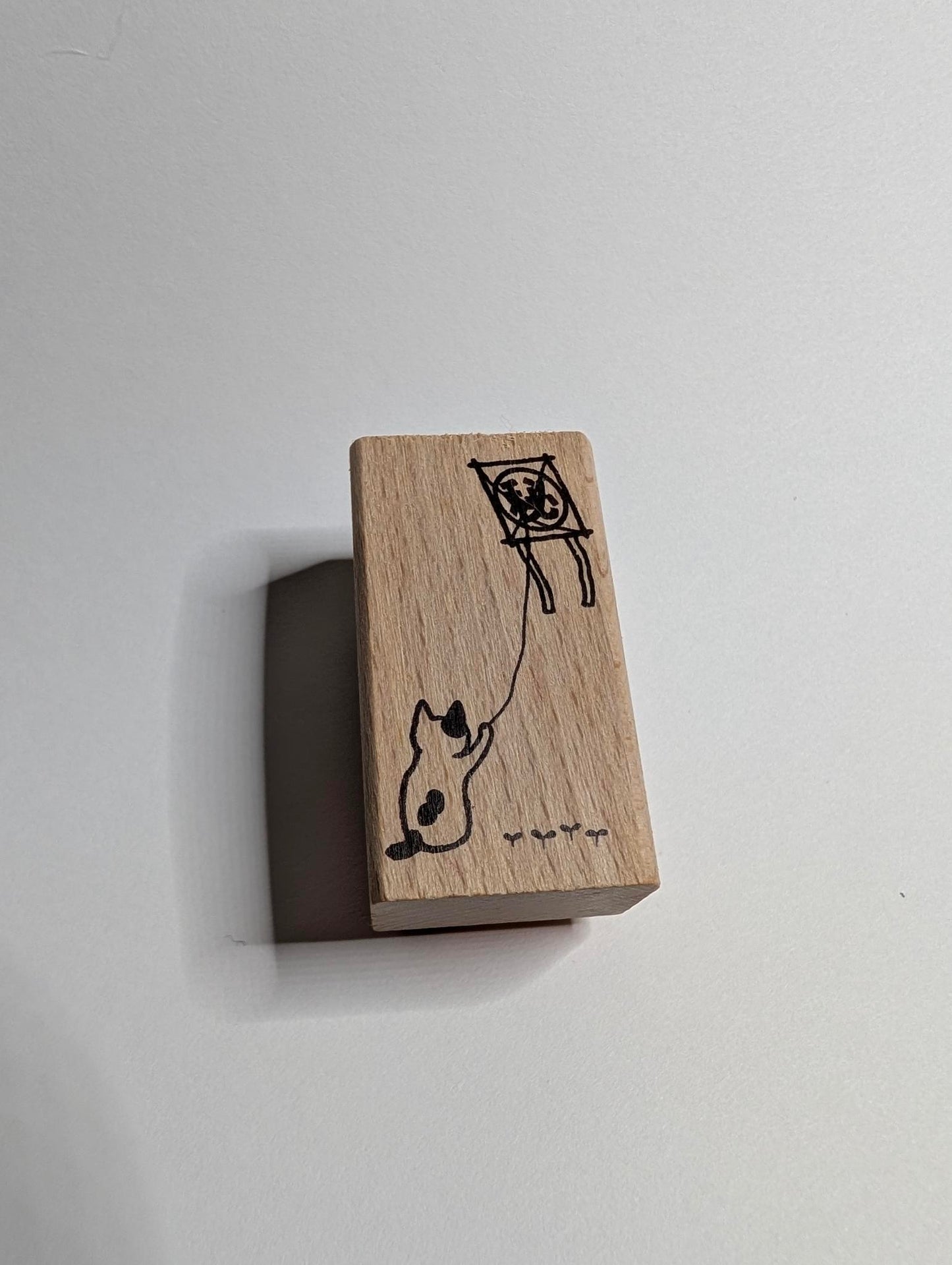 Wooden block with a cat and kite illustration on a white background