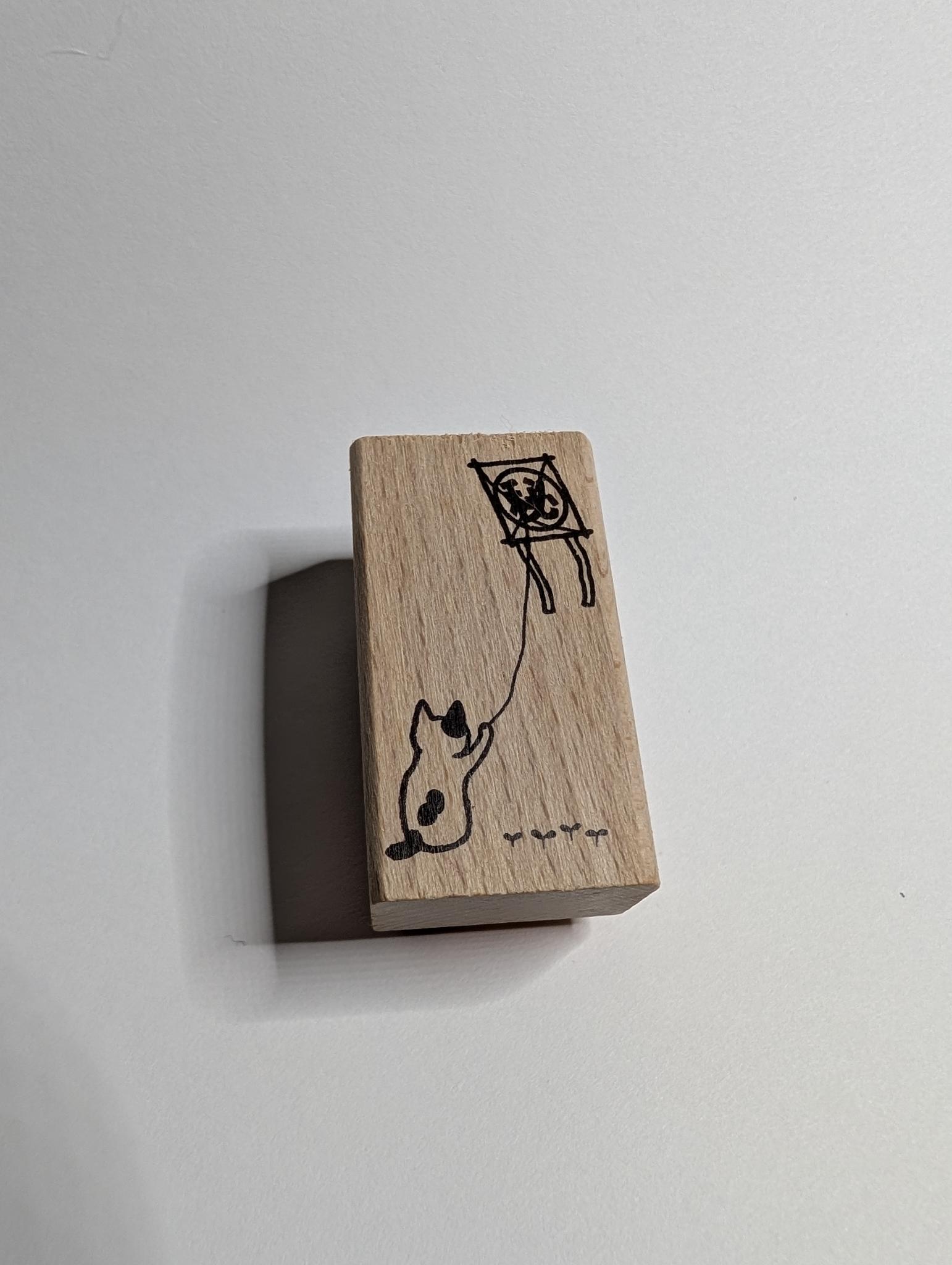 Wooden block with a cat and kite illustration on a white background